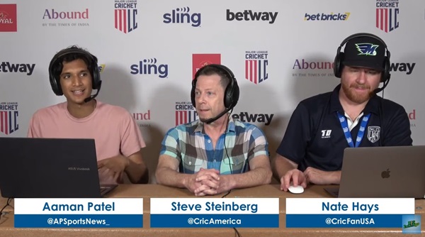 Three men sitting at a table with headphones on.