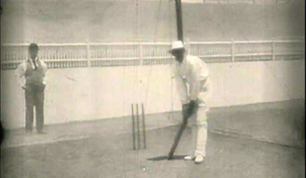 A man in white shirt and hat holding a bat.